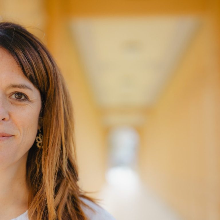 Gesangsunterricht Online und in Baldham Nahaufnahme einer Frau mit braunen Haaren in einem hellen, orangefarbenen Gang.